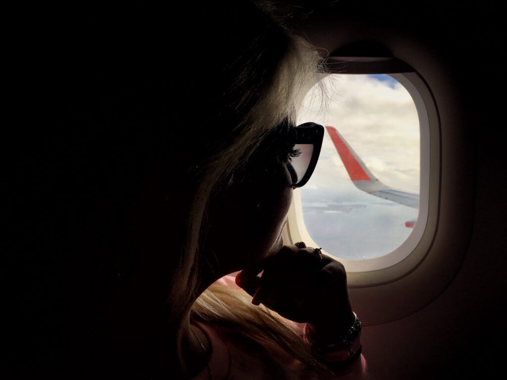 Como dormir en un avión: 13 consejos para los viajeros 11 1632435428 290 a millennial girl sitting by the window on an airplane while traveling t20 mo407m