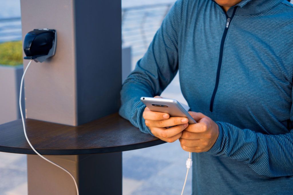 10 cosas que hacer en el aeropuerto gratis 15 Persona cargando su teléfono móvil en una estación de carga del aeropuerto