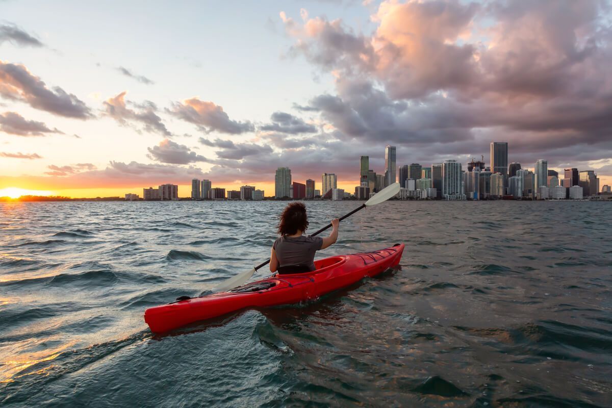 donna in kayak nell'acqua di fronte allo skyline di miami