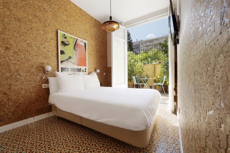 Escapada romántica a Barcelona - Los mejores hoteles 5 Un dormitorio en Roca Rooms & Apartments con una cama, lámparas de cabecera, arte en la pared, suelo de baldosas y puertas que dan a un espacio exterior